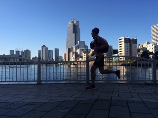 Silhouette of man running to work in city