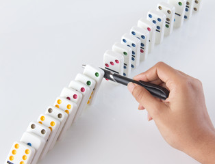 Person stopping falling dominoes with a pen