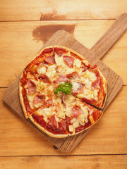 Hawaiian pizza on wood plate