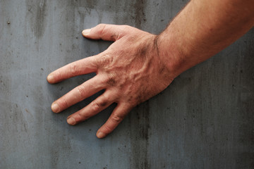 Male hand touching the surface of a concrete wall - obrazy, fototapety, plakaty