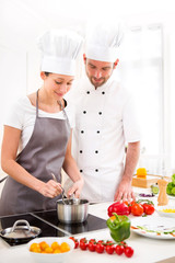 Young chef training a young attractive girl to cook
