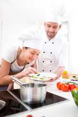 Young chef training a young attractive girl to cook