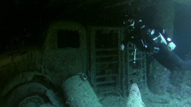 Diver looking at cars in the hold of a sunken ship Thistlegorm 