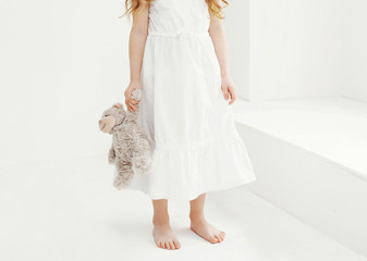 Little girl holding teddy bear in white room