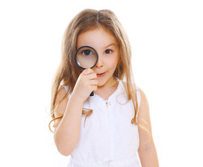 Portrait of funny little girl looking through a magnifying glass