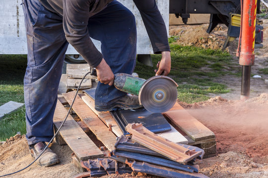 Worker using a hand circular saw to cut a roof-tile