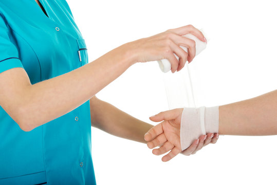 Woman doctor bandaging female hand.
