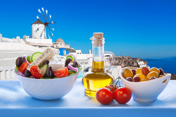 Greek salad against windmill in Santorini island, Greece