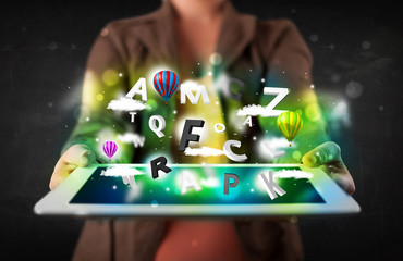 Young person showing tablet with abstract letters and sky