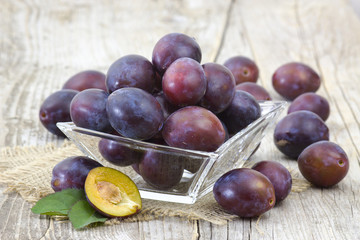 Fototapeta premium fresh plums in a bowl on old wooden background