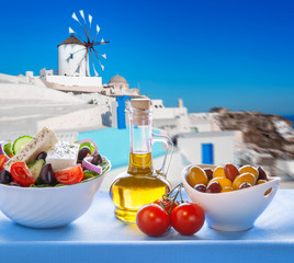 Greek salad against windmill in Santorini island, Greece