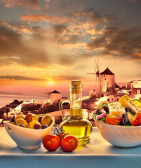 Greek salad against windmill in Santorini island, Greece