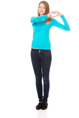 Fototapeta premium Smiling teenage woman making heart shape