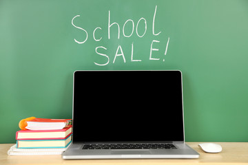 Laptop on table, on green blackboard background