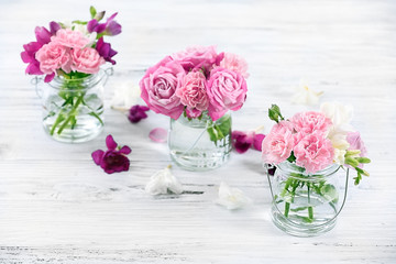 Beautiful spring flowers in glass bottles on wooden background