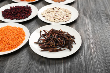 Different products on saucers on wooden table, closeup