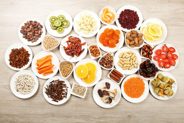 Different products on saucers on wooden table, top view