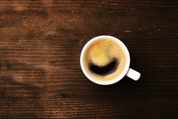 Cup of coffee on wooden table, top view