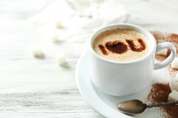 Cup of latte coffee art on wooden table, on light background