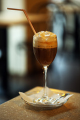 Glass of coffee with cream on table in cafe