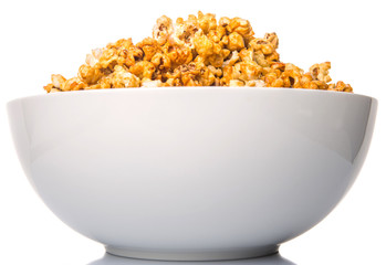 Caramel popcorn in white bowl over white background