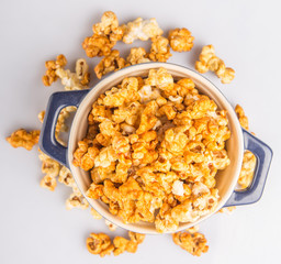 Caramel popcorn in blue pot over white background