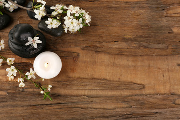 Spa stones with candle and spring flowers on wooden background