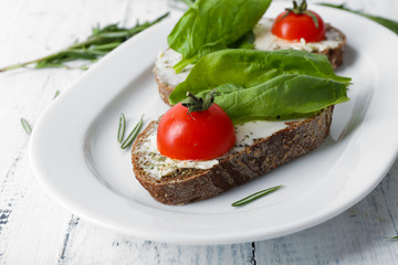Delicious sandwiches with tomatoes and greens on plate table close up