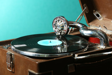 Gramophone with vinyl record on table on green background