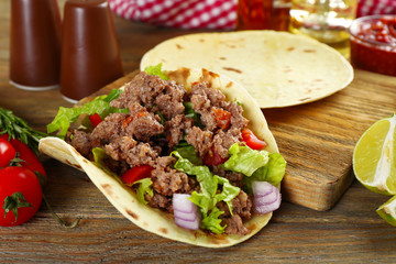 Mexican food Taco on wooden cutting board, closeup