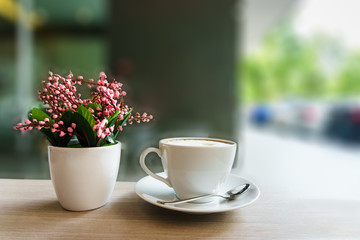 coffee cup and flower on wooden table in coffee shop