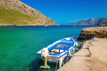 Fototapeta na wymiar Small open-deck motor boat in Greek colors in port at the bay of