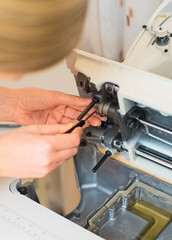 Female hand fixing sewing machine. Maintenance.