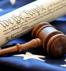 Democracy. The Constitution along with a wooden judge's gavel atop an American flag
