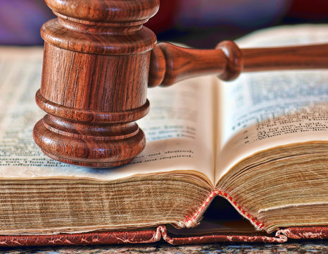 Closeup of a wooden gavel atop a legal book.