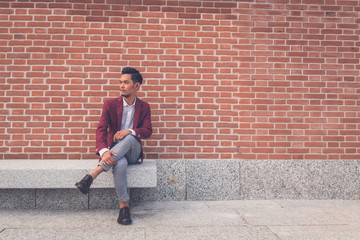 Fototapeta na wymiar Handsome Asian model sitting in the city streets