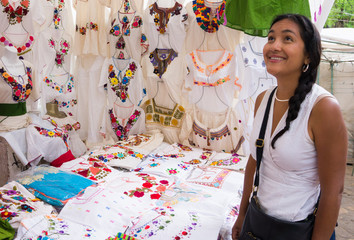 Hispanic woman admiring embroidered  Mexican blouses