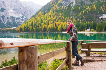 Fototapeta na wymiar Woman hiker rests on a wooden railing, facing Lake Bries