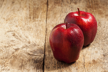 Red apples with water drops on a wooden table, selective focus