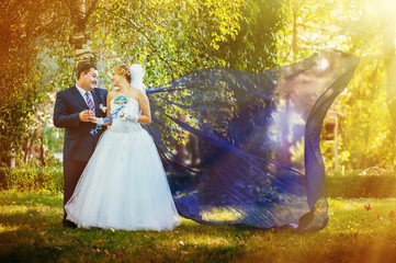 Bride and groom in the park with flying fabric.