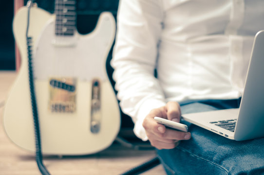Guitarist uses a smartphone and computer