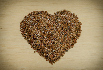 Raw flax seeds linseed heart shaped on wooden table