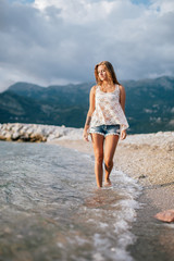 Fototapeta na wymiar dreamy fashion girl walk on beach with mountains background