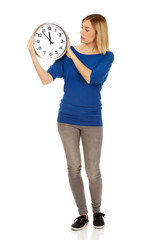 Shocked woman holding a clock.