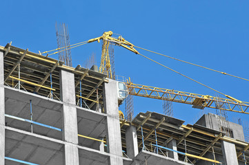 Crane and building construction site against blue sky