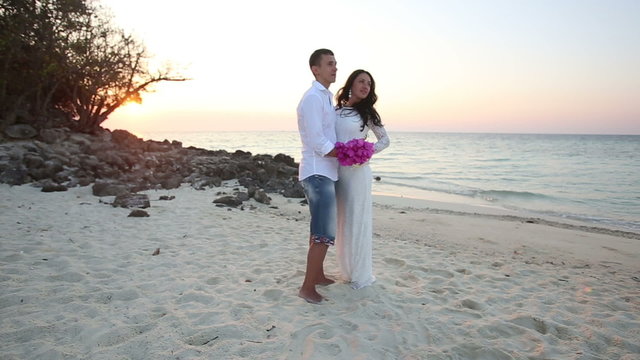 bride and groom hug and laugh at sand beach at dawn	