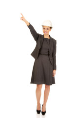 Businesswoman in hard hat pointing up.