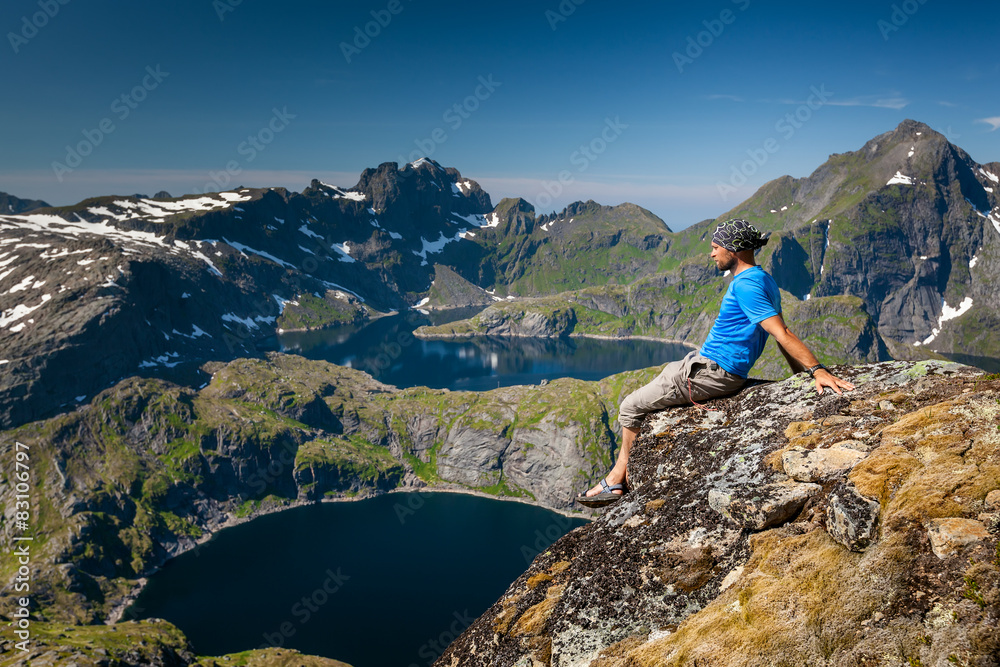 Wall mural man takes rest on top of mountain in norway