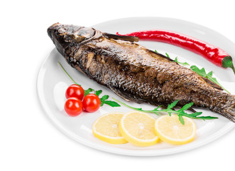 Grilled carp with vegetables on plate.