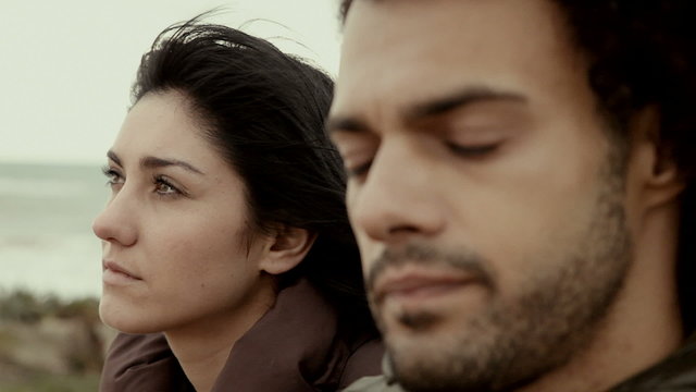 Man and woman angry at each other talking in front of the ocean